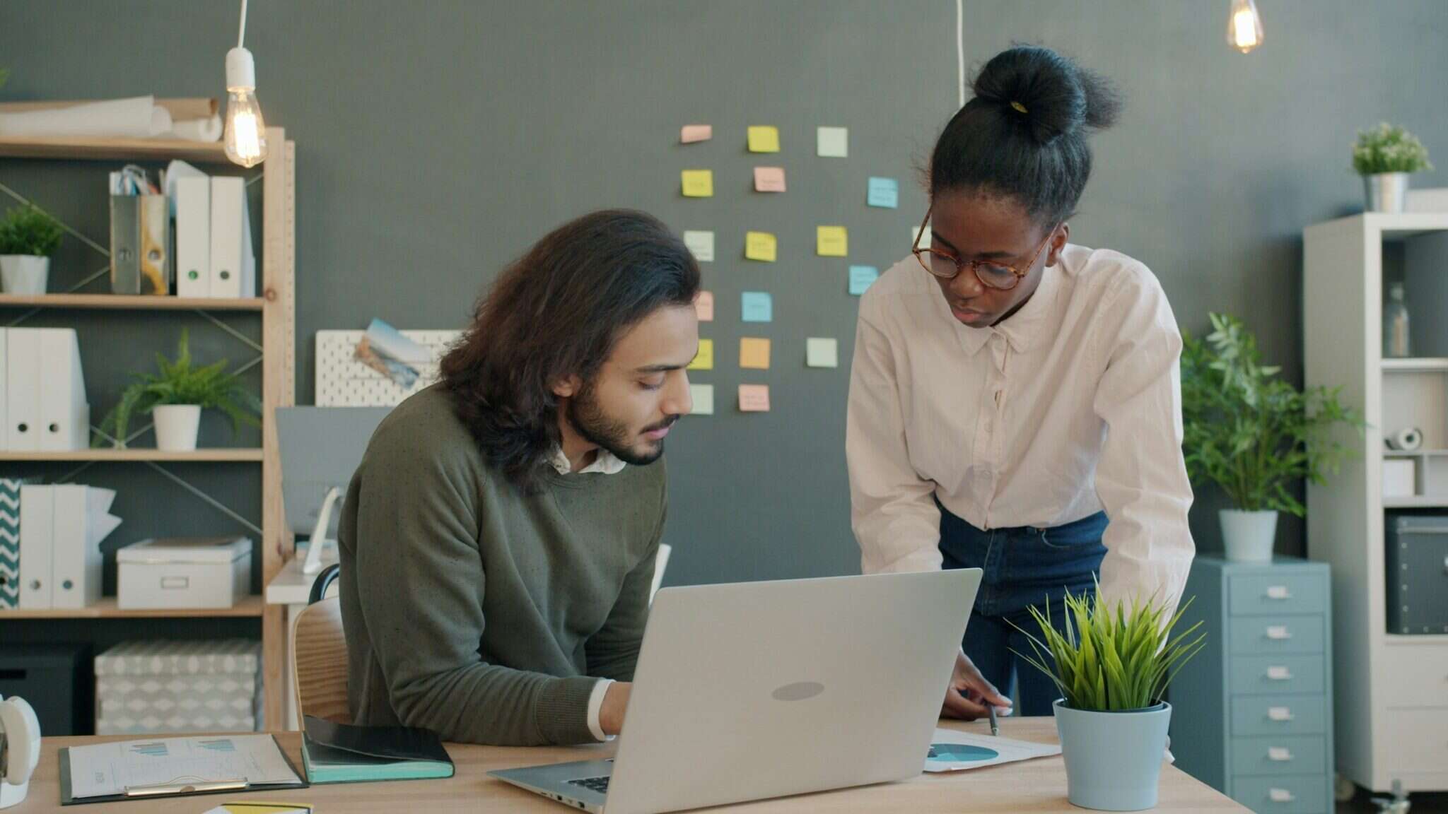 Two colleagues working through customer requests together at a desk with a laptop and notes