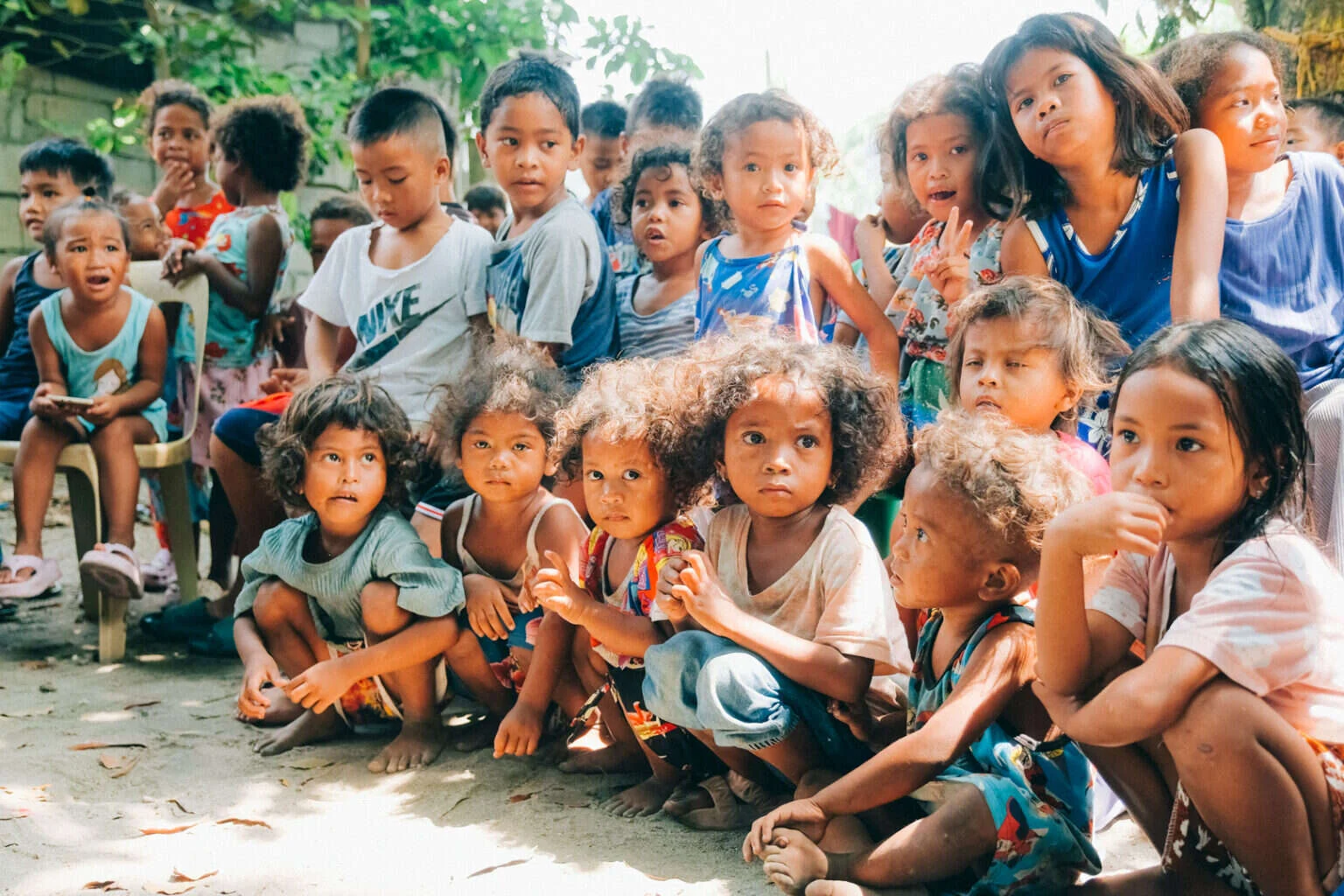 A large group of children seated and looking toward the camera